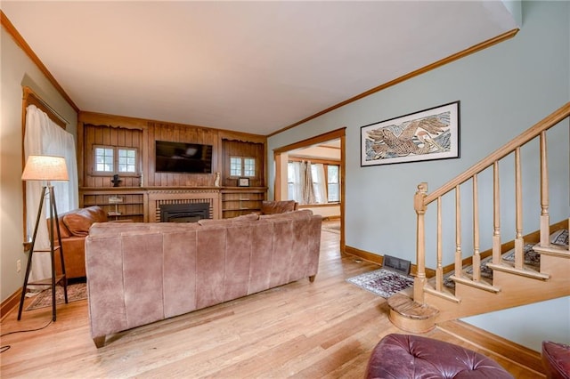 living room with a healthy amount of sunlight, light hardwood / wood-style flooring, a fireplace, and crown molding