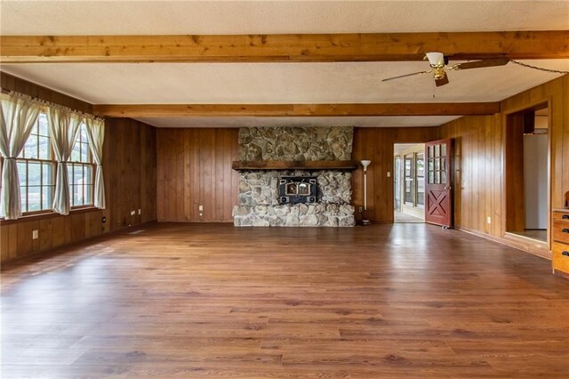 unfurnished living room with hardwood / wood-style flooring, a wealth of natural light, and wooden walls