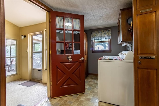 washroom featuring light carpet, washer and clothes dryer, cabinets, and a textured ceiling