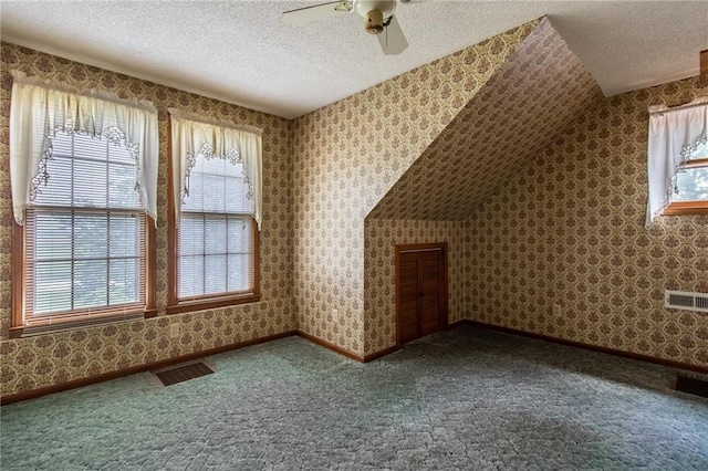 bonus room featuring lofted ceiling, plenty of natural light, ceiling fan, and a textured ceiling