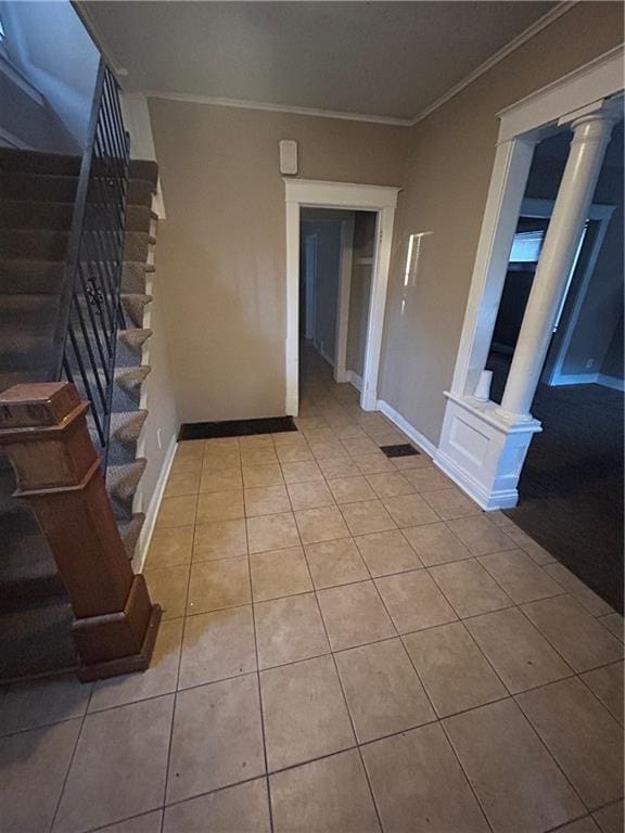 interior space featuring tile patterned flooring, stairs, decorative columns, and crown molding