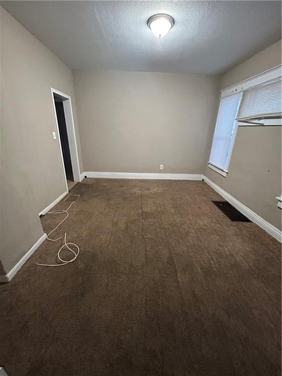 carpeted spare room with a textured ceiling and baseboards