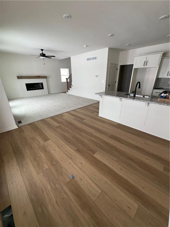 kitchen with sink, backsplash, dark stone counters, white cabinets, and hardwood / wood-style flooring