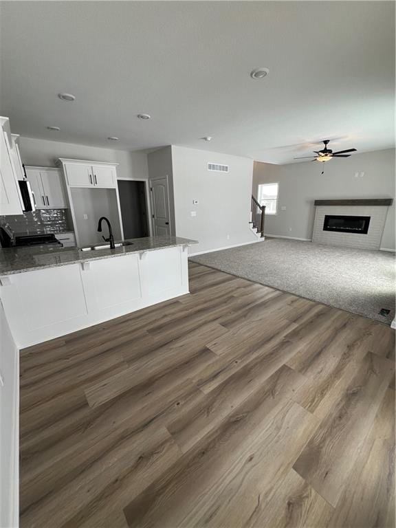 kitchen with white cabinetry, sink, dark wood-type flooring, kitchen peninsula, and decorative backsplash