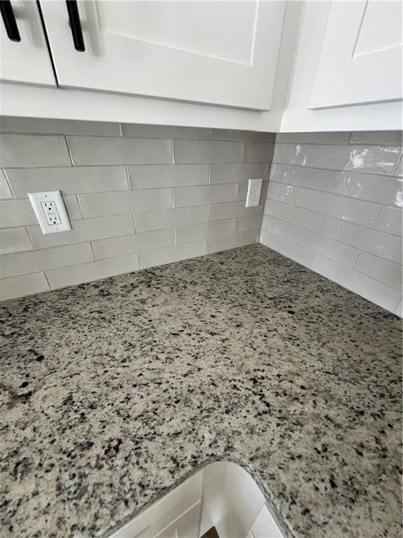 details featuring decorative backsplash, light stone counters, and white cabinetry