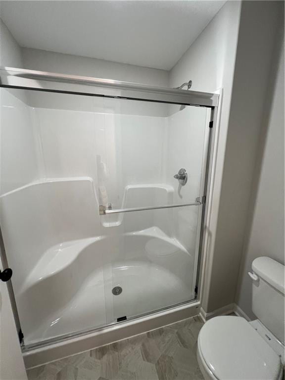 bathroom with a shower with shower door and toilet