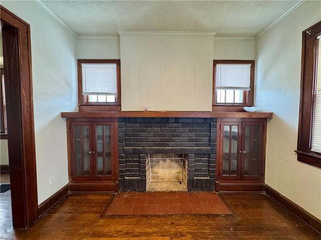 unfurnished living room featuring a fireplace, dark wood-type flooring, a textured ceiling, and ornamental molding