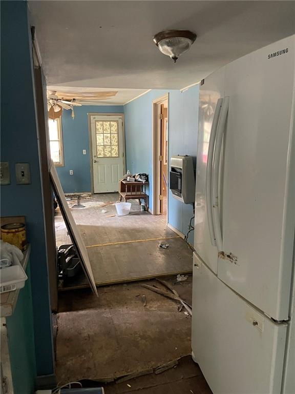 kitchen featuring ceiling fan, heating unit, and white fridge