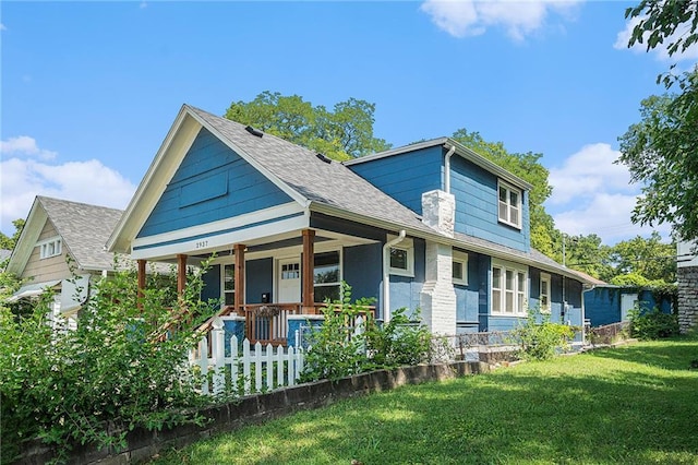 view of front of home featuring a fenced front yard, roof with shingles, covered porch, and a front lawn