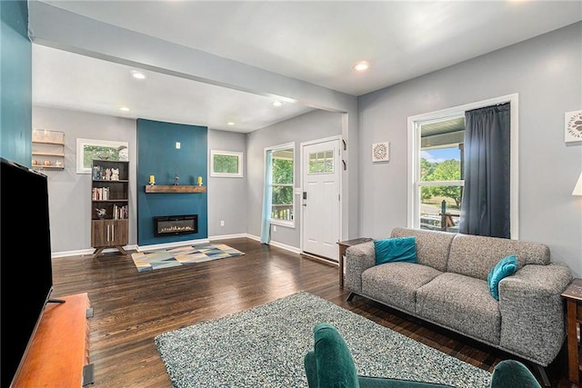 living room featuring a glass covered fireplace, recessed lighting, wood finished floors, and baseboards