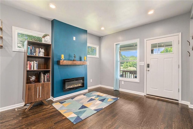 entrance foyer with visible vents, baseboards, recessed lighting, wood finished floors, and a glass covered fireplace