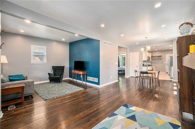 living room with recessed lighting, visible vents, and wood finished floors