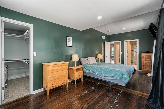 bedroom with a walk in closet, hardwood / wood-style flooring, baseboards, and a closet