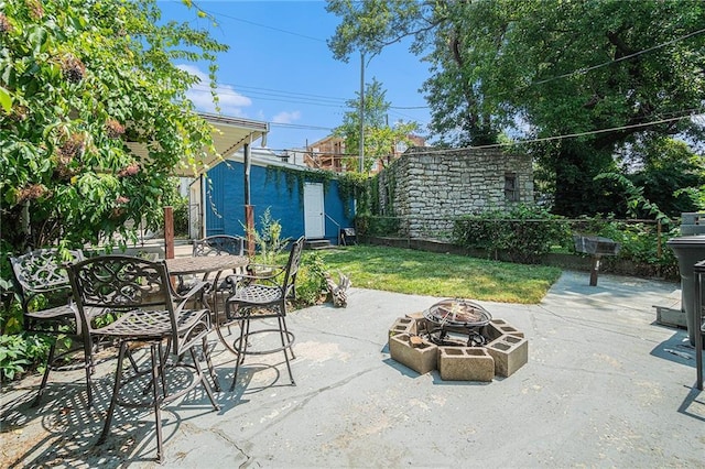 view of patio / terrace with outdoor dining space, an outdoor structure, a fire pit, and fence