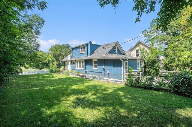 rear view of property featuring fence and a lawn