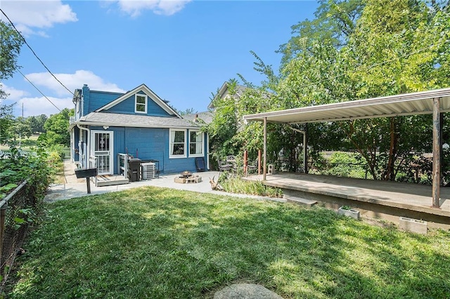 back of property with a patio area, a lawn, and an outdoor fire pit