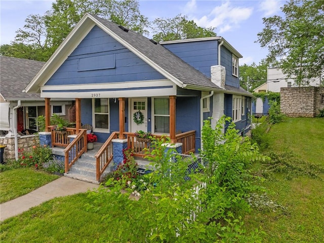 2937 Paseo Blvd, Kansas City, MO 64109 - bungalow-style house with covered porch, roof with shingles, and a front yard