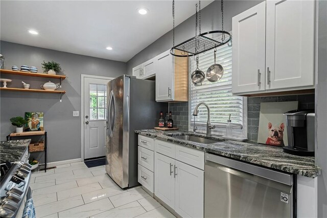 2937 Paseo Blvd, Kansas City, MO 64109 - kitchen with stainless steel appliances, a sink, dark stone countertops, backsplash, and white cabinetry