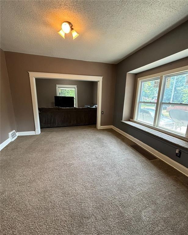 carpeted spare room featuring a textured ceiling