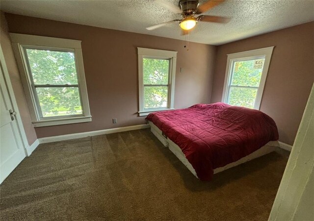 bedroom with a textured ceiling, ceiling fan, and dark carpet