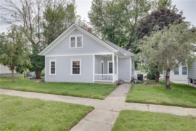 view of front of property with a front lawn, a porch, and central AC