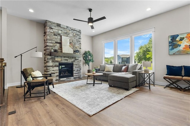 living room featuring ceiling fan, a fireplace, and light hardwood / wood-style floors