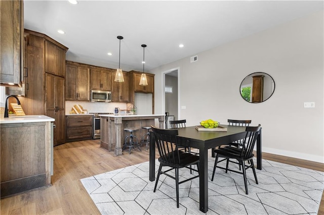 dining area with light wood-type flooring and sink