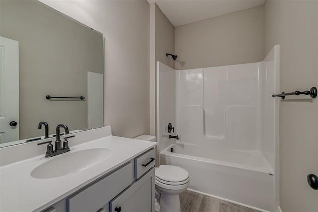 full bathroom with toilet, washtub / shower combination, vanity, and wood-type flooring