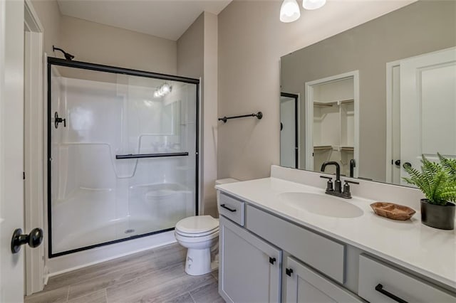 bathroom with an enclosed shower, toilet, vanity, and hardwood / wood-style flooring