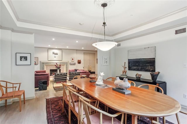 dining room with ornamental molding, a raised ceiling, visible vents, and a high end fireplace