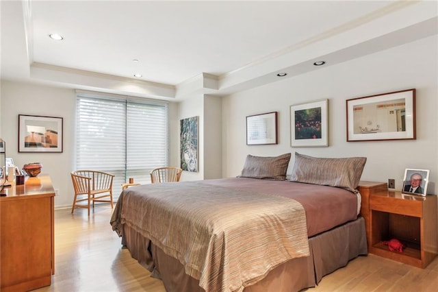 bedroom with crown molding, a tray ceiling, recessed lighting, and light wood-style floors