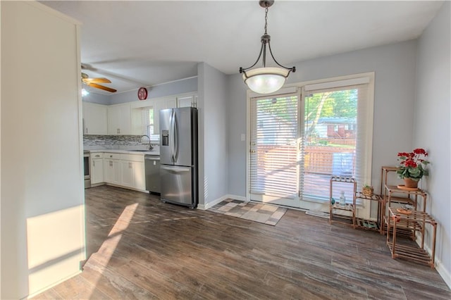 kitchen with white cabinets, appliances with stainless steel finishes, ceiling fan, dark hardwood / wood-style floors, and pendant lighting