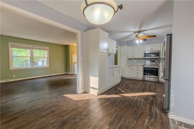 kitchen with white cabinets, appliances with stainless steel finishes, dark hardwood / wood-style flooring, ceiling fan, and tasteful backsplash