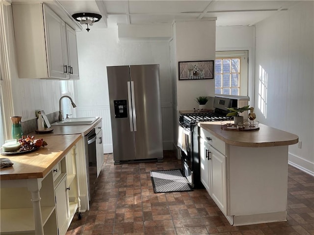 kitchen with white cabinets, stainless steel appliances, butcher block countertops, and sink