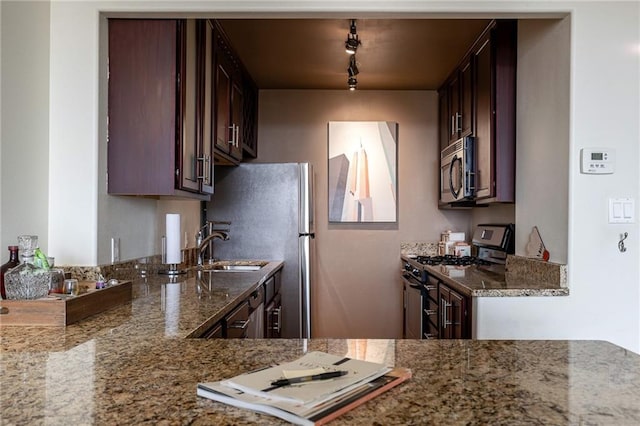 700 E 8th St Unit 11P, Kansas City, MO 64106 - kitchen featuring stainless steel appliances, stone counters, rail lighting, a sink, and dark brown cabinetry