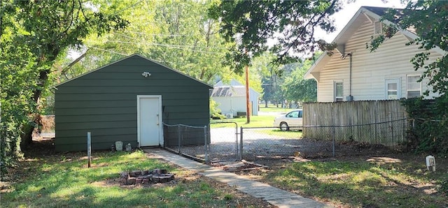 view of outdoor structure with an outbuilding, fence, and a fire pit