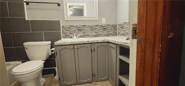 full bathroom featuring toilet, tasteful backsplash, vanity, and tile walls