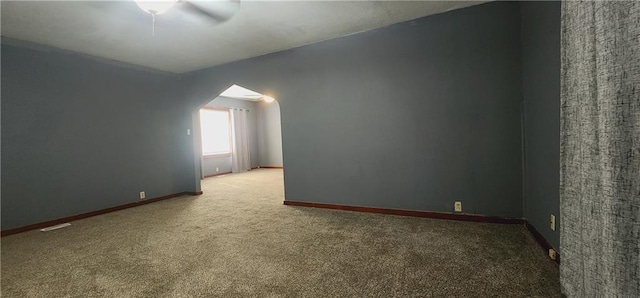 additional living space featuring arched walkways, ceiling fan, visible vents, baseboards, and dark colored carpet