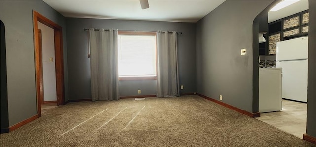 empty room featuring arched walkways, light carpet, a ceiling fan, and baseboards