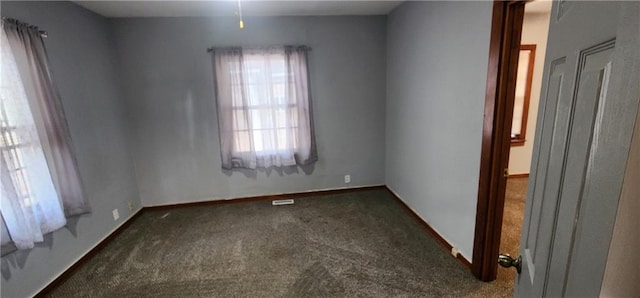 empty room with baseboards and dark carpet