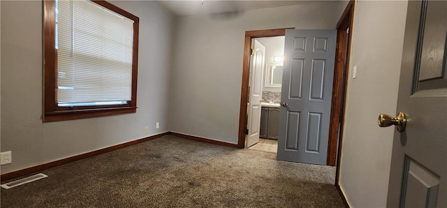 unfurnished bedroom with light carpet, ensuite bath, visible vents, and baseboards