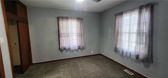 carpeted spare room featuring visible vents and baseboards