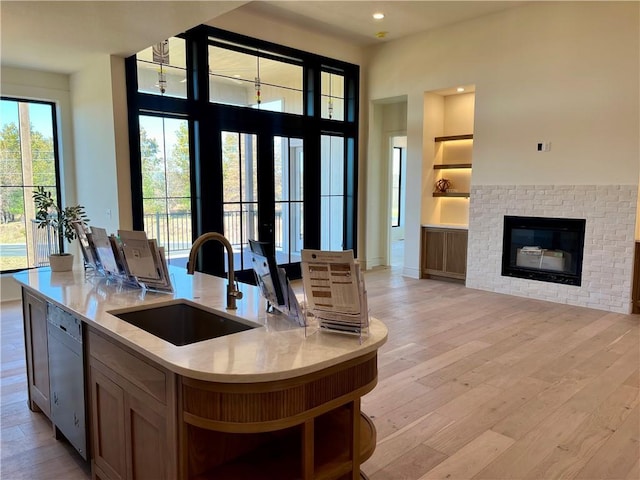 kitchen with open floor plan, open shelves, light wood-style floors, and a sink