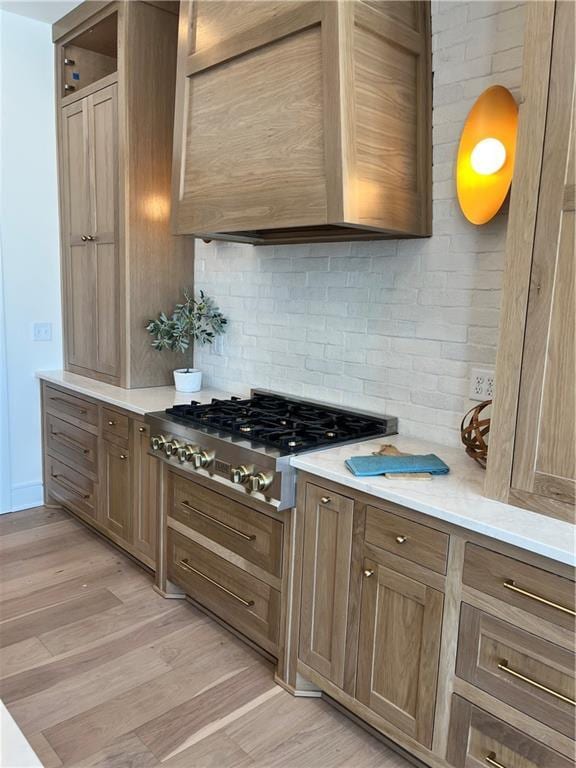 kitchen with light countertops, light wood-style flooring, tasteful backsplash, and stainless steel gas cooktop