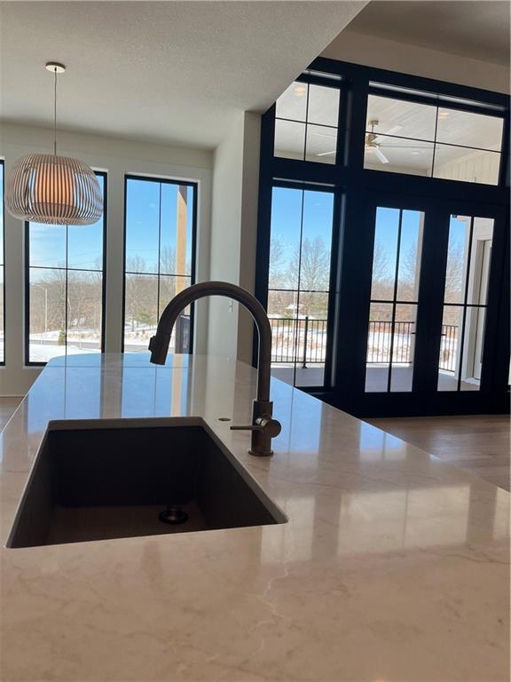 room details featuring a sink, decorative light fixtures, and light stone counters