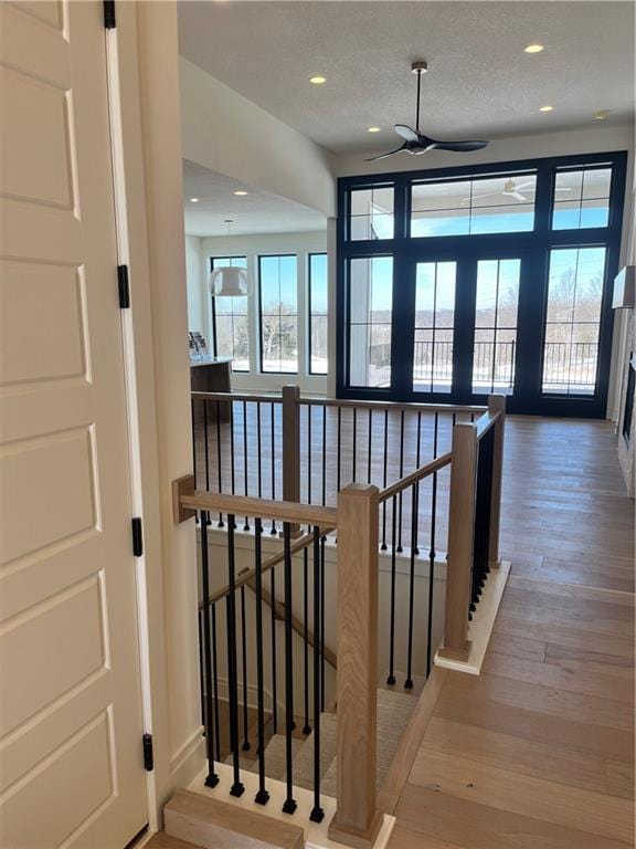 staircase with recessed lighting, wood finished floors, and a textured ceiling