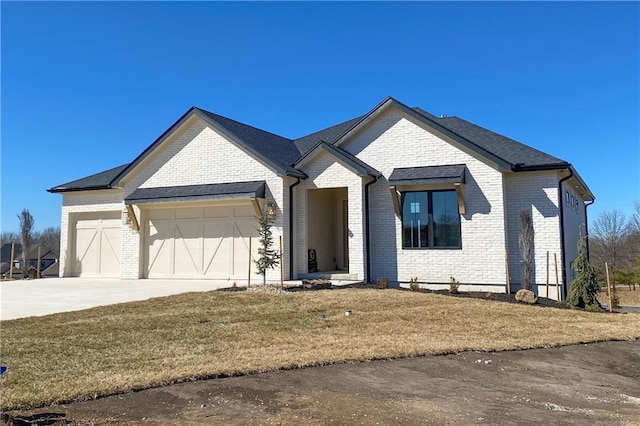 view of front of home with a front yard, an attached garage, brick siding, and driveway