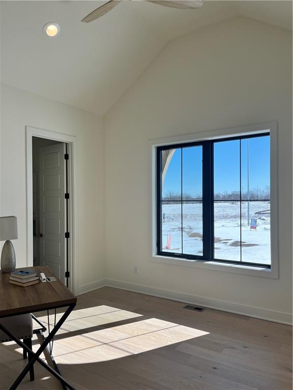 interior space with visible vents, baseboards, wood finished floors, and vaulted ceiling