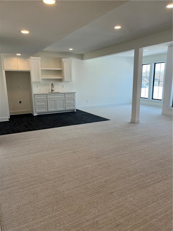 interior space featuring a sink, baseboards, recessed lighting, and dark carpet