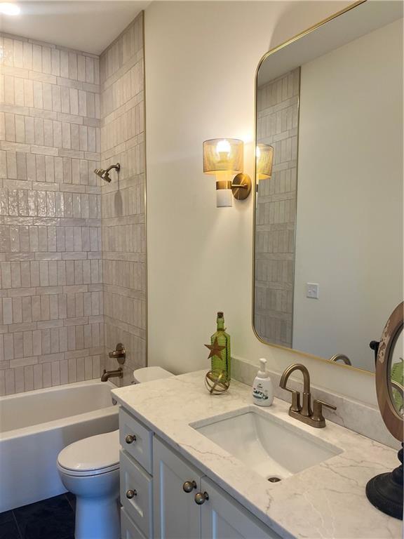 bathroom featuring toilet, vanity, and bathtub / shower combination